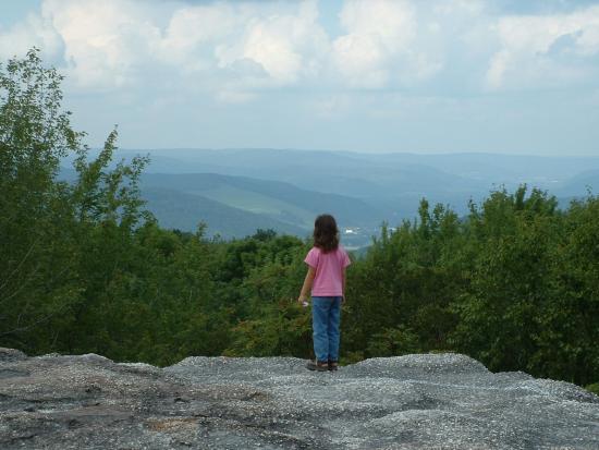 Little Girl standing on a huge rock overlooking the hills and valleys