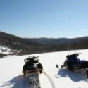 Two snowmobiles in the foreground with a Great View of the hillsides